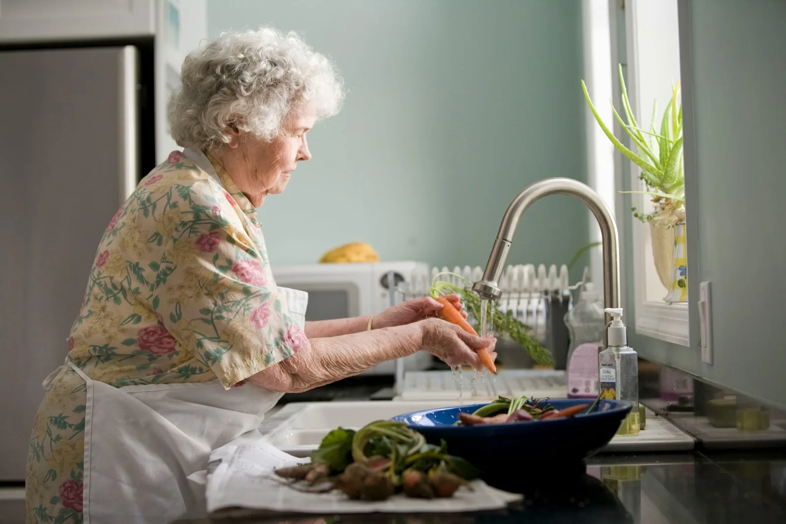 Femme âgée préparant ses légumes dans sa cuisine